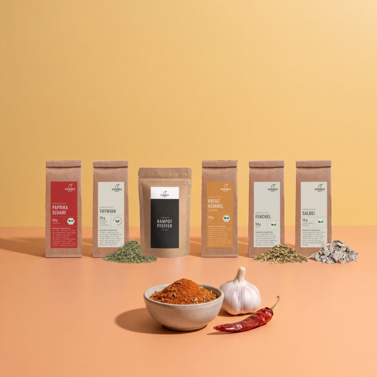 Cajun-Gewürz: Schale mit der Mischung, dahinter die Zutaten Paprika scharf, Thymian, schwarzer Kampot-Pfeffer, Kreuzkümmel, Fenchelsamen und Salbei im Gewürzstudio-Beutel