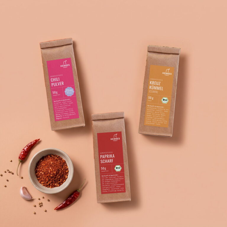 Harissa-Gewürz von oben: Schale mit der Mischung und die Zutaten Chilipulver, Kreuzkümmel und Paprika scharf im Gewürzstudio-Beutel