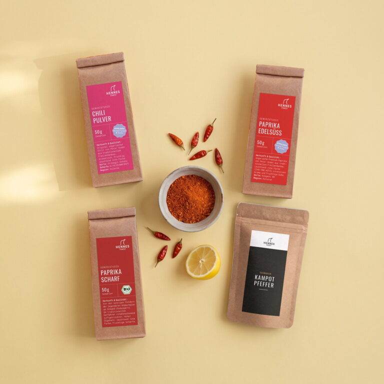 Piri-Piri-Gewürz von oben: Schale mit der Mischung und die Zutaten Chilipulver, Paprika edelsüß, Paprika scharf und schwarzer Kampot-Pfeffer im Gewürzstudio-Beutel