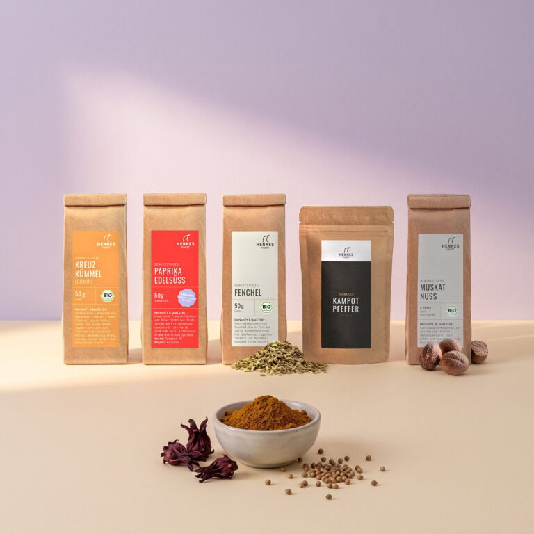 Purple Curry: Schale mit der Mischung, dahinter die Zutaten Kreuzkümmel, Paprika edelsüß, Fenchelsamen, schwarzer Kampot-Pfeffer und Muskatnuss im Gewürzstudio-Beutel