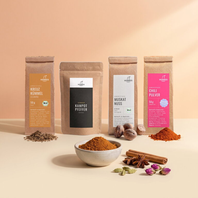 Ras el Hanout: Schale mit der Mischung, dahinter die Zutaten Kreuzkümmel, schwarzer Kampot-Pfeffer, Muskatnuss und Chilipulver im Gewürzstudio-Beutel