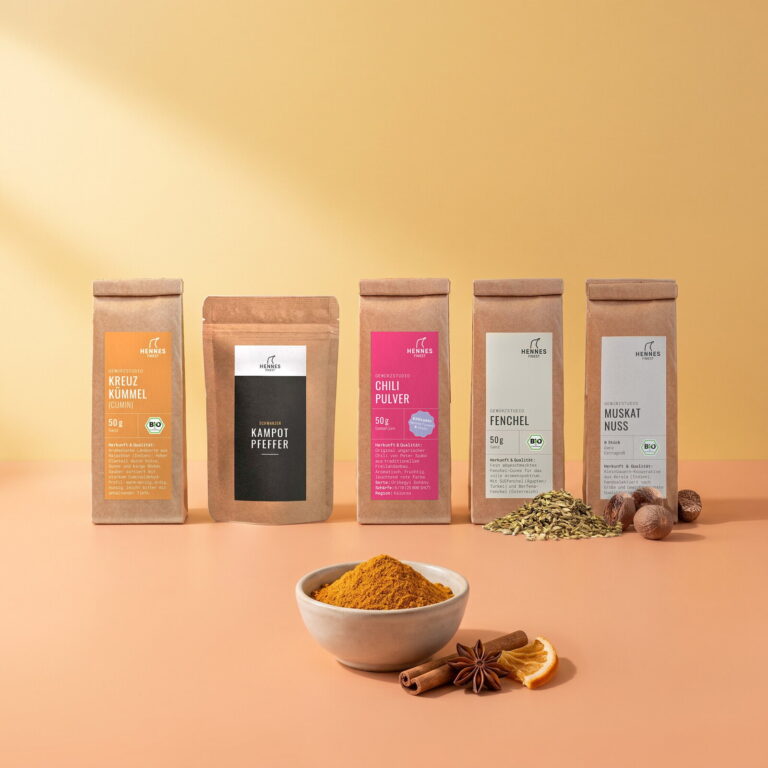 Tajine-Gewürz: Schale mit der Mischung, dahinter die Zutaten Kreuzkümmel, schwarzer Kampot-Pfeffer, Chilipulver, Fenchelsamen und Muskatnuss im Gewürzstudio-Beutel