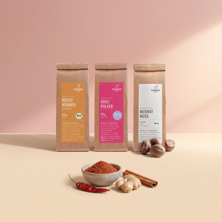 Tandoori Masala: Schale mit der Mischung, dahinter die Zutaten Kreuzkümmel, Chilipulver und Muskatnuss im Gewürzstudio-Beutel